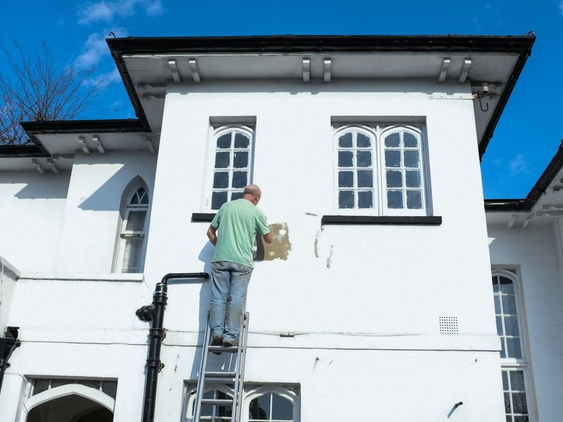 Pintor na escada pintando fachada