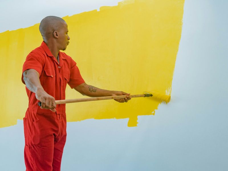 Pintor pintando parede de amarelo